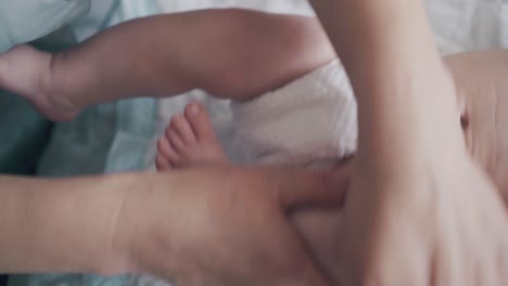 nurse massages flexes and stretches lying in bed infant legs