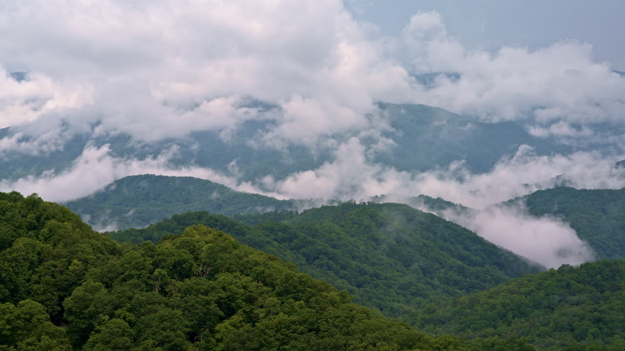 Wide drone shot of cloudy skies pressing into mist-filled Smoky valleys