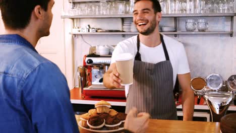 Waiter-giving-coffee-to-young-customer-at-counter