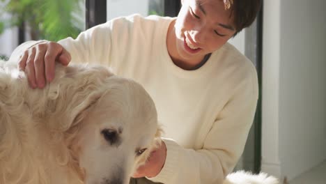 Happy-asian-male-teenager-petting-his-dogs-in-living-room