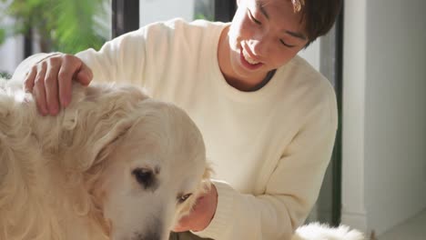 Glücklicher-Asiatischer-Männlicher-Teenager,-Der-Seine-Hunde-Im-Wohnzimmer-Streichelt