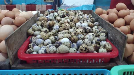 Pile-of-quail-eggs-in-the-middle-of-chicken-eggs-in-a-market