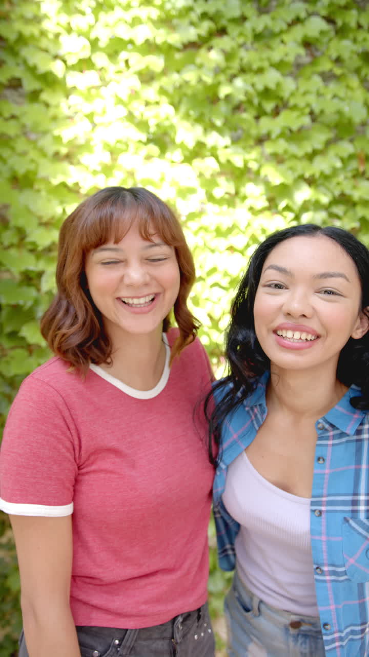 Vertical video: Standing together outdoors, two women smiling and enjoying sunny day