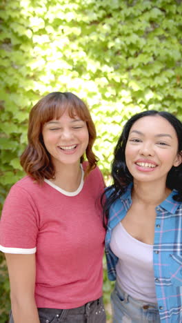 vertical video: standing together outdoors, two women smiling and enjoying sunny day