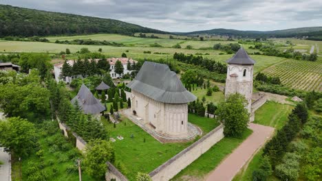 drone video of dobrovat monastery in romania, showing the church and surrounding forest from an aerial perspective