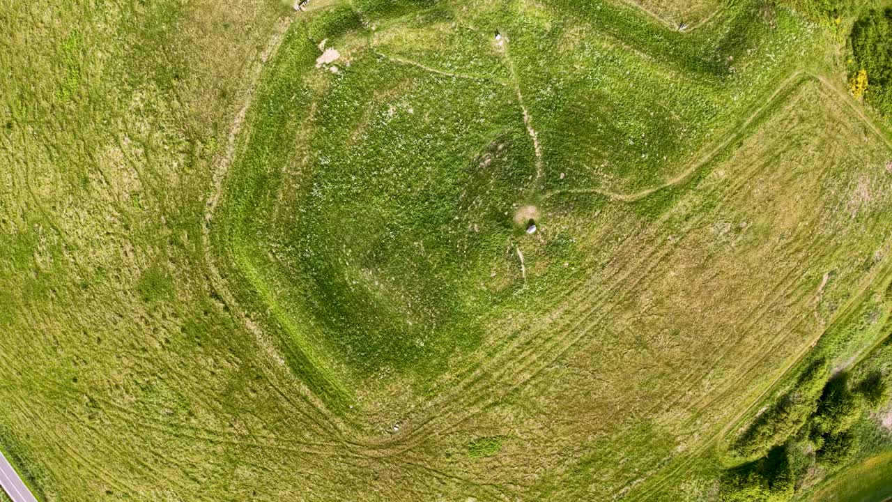 Aerial top-down view of Ryes Skanse, a circular historic military fortification surrounded by grassy terrain. Earthwork embankments and walking paths are clearly visible from above