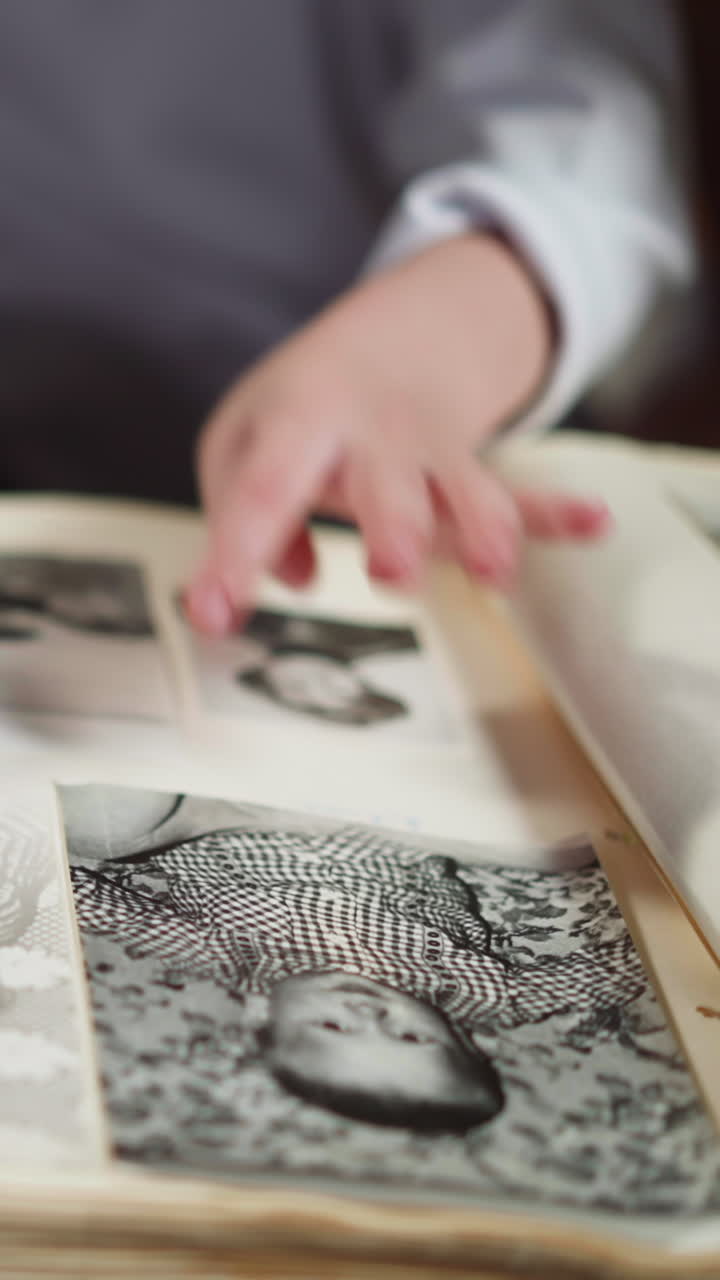 Little daughter shows pictures of babies grandparents by finger to African-American step-father sitting at small table closeup slow motion