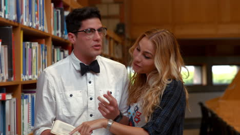 estudiante bonita hablando con un nerd en la biblioteca
