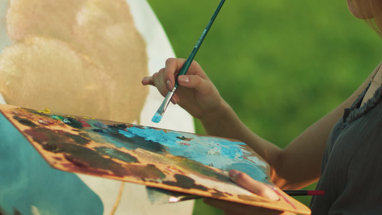 Pittrice donna che mescola colori a olio sulla tavolozza d'artista con il pennello