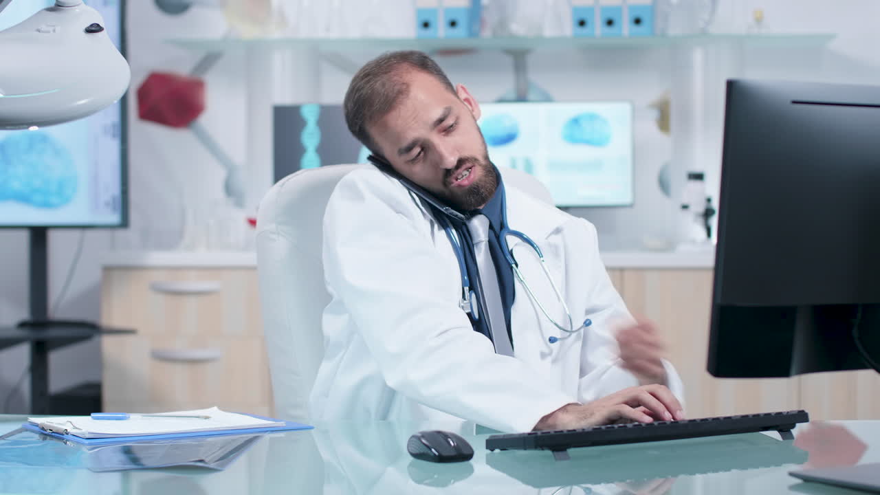 Doctor on a Phone Call at His Computer