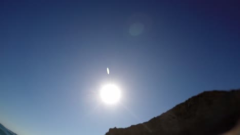 View-of-horizon-with-big-sun-behind-cliff-from-water-surface-at-sea