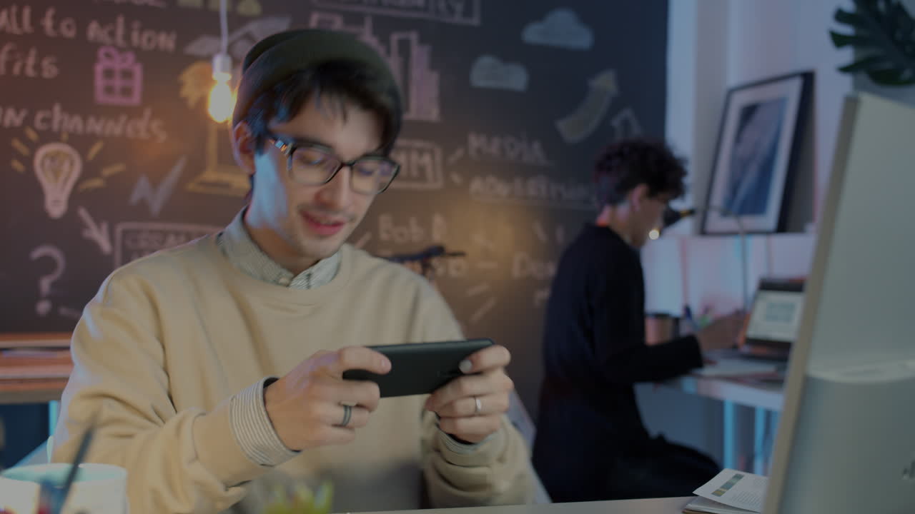 Young Man Playing Mobile Game in Modern Office