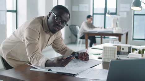 portrait of black male architect drawing floor plan with smartphone