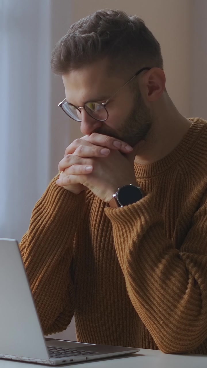 Giovane uomo concentrato che lavora al laptop nel suo ufficio domestico