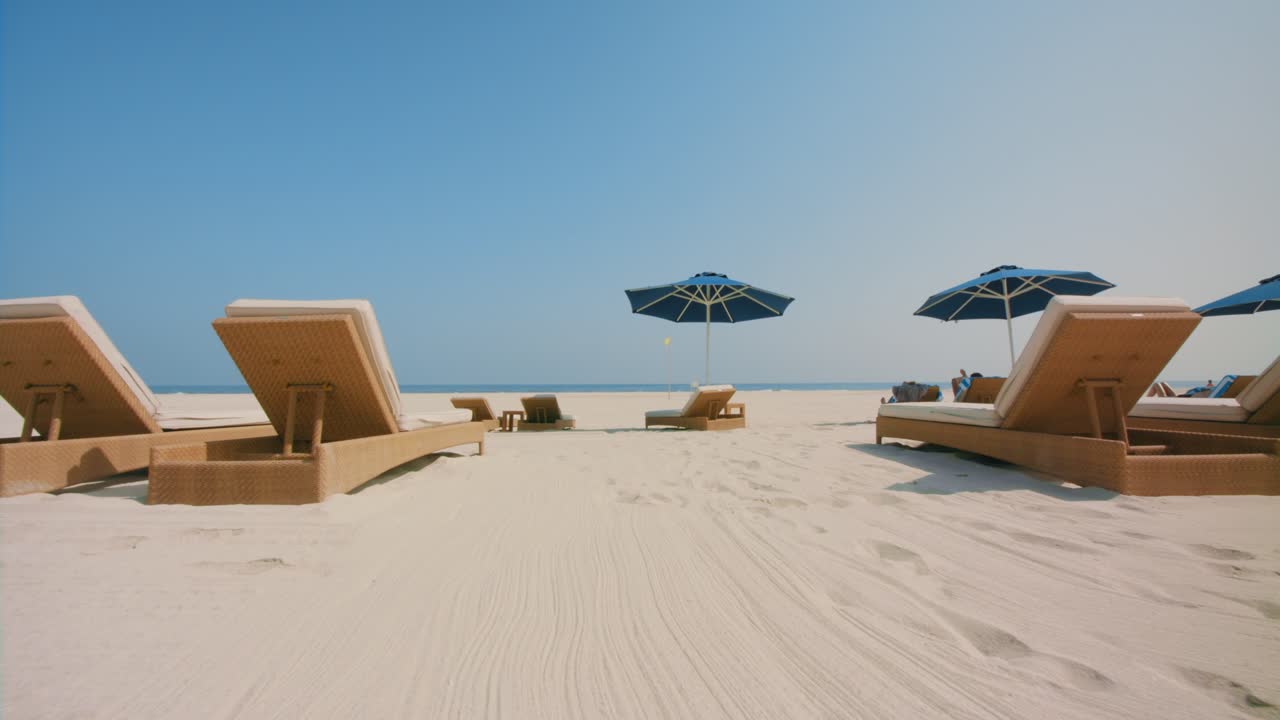 Approaching the white sand beach with great ambient, passing sunbath beds to the blue sea ocean beach waves, 4k footage