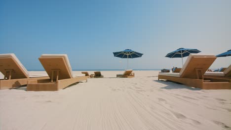 approaching the white sand beach with great ambient, passing sunbath beds to the blue sea ocean beach waves, 4k footage