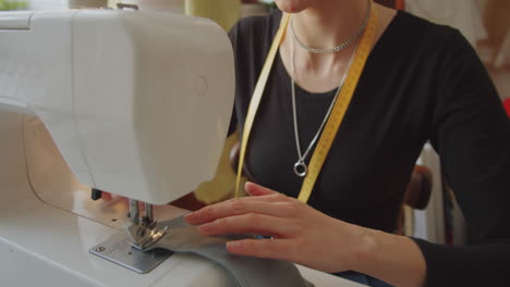 woman using sewing machine in dressmaking studio