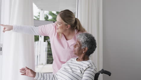 smiling caucasian nurse talking with senior african american woman patient, slow motion