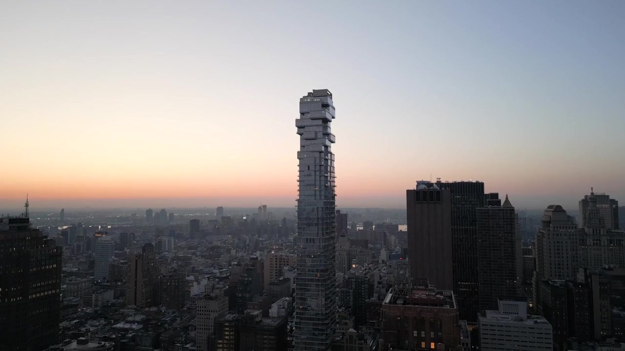 New York City, Tribeca Downtown. Riprese aeree con drone della torre Jenga che si allontana con movimento di inclinazione, rivelando il cielo dorato e blu all'alba, in 4K a 60fps.