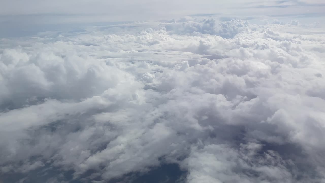 View from the window of a plane over fluffy clouds in the sky