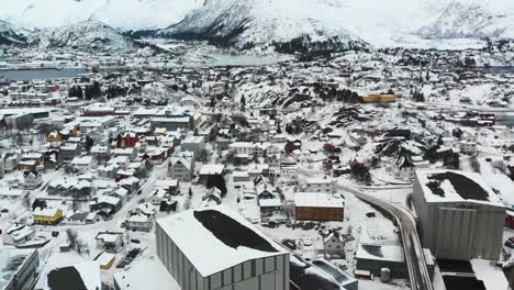 Carretera-Noruega-En-Un-Puerto-Con-Algunos-Barcos-Durante-El-Invierno-Con-Las-Montañas-Al-Fondo-En-Las-Islas-Lofoten