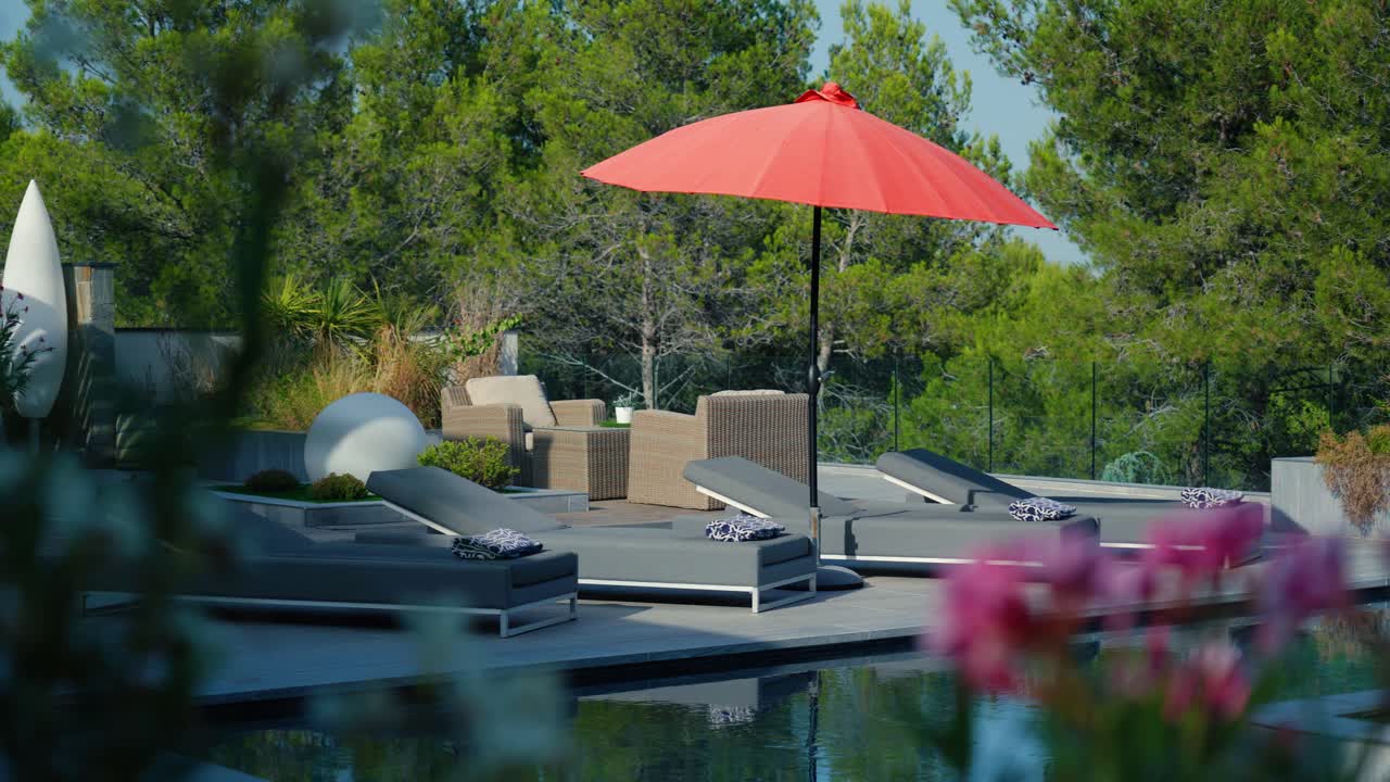 Scenic poolside with sunbeds and an ubrella in the sunny garden of a french villa