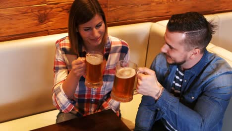 una pareja brindando por un vaso de cerveza.