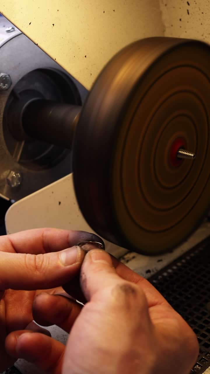Primo piano delle mani che lucidano un piccolo oggetto di metallo in un laboratorio