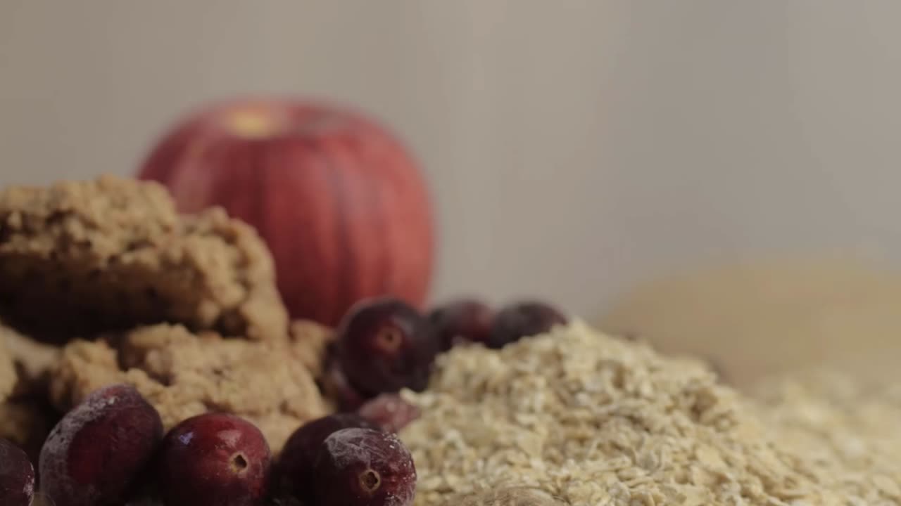 Healthy ingredients of dry rolled oats with cranberries and cookies panning medium panning shot