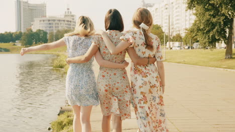 three women walking together in a park by the lake