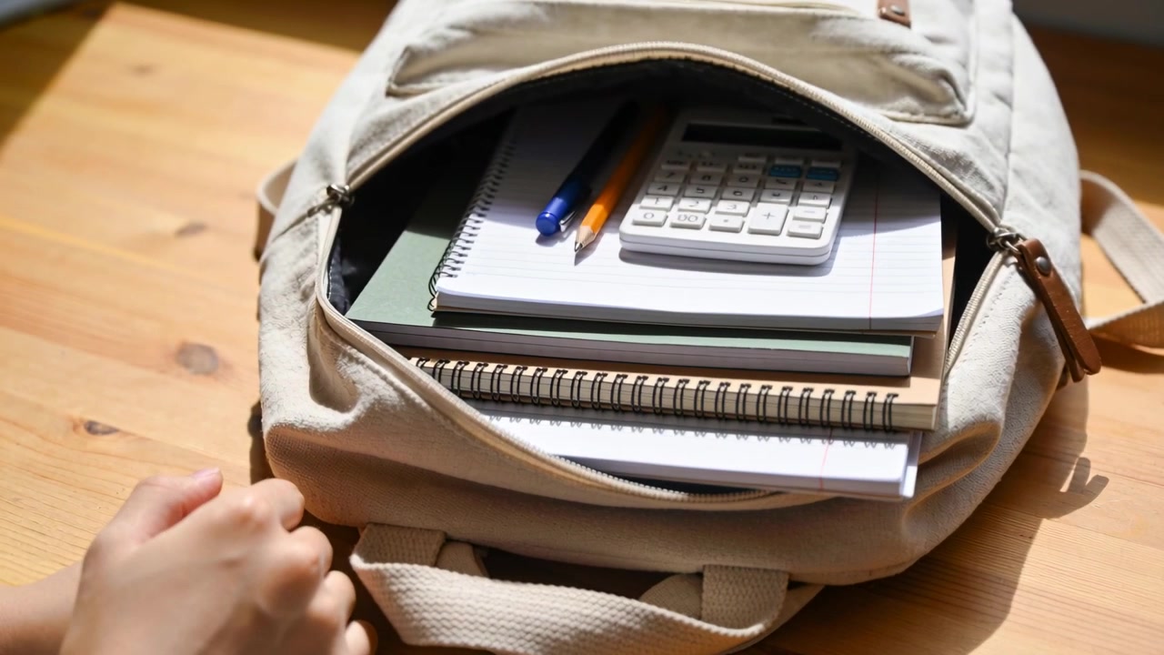 Placing backpack on table hands opening pocket and arranging notebooks, calculator, pens for study