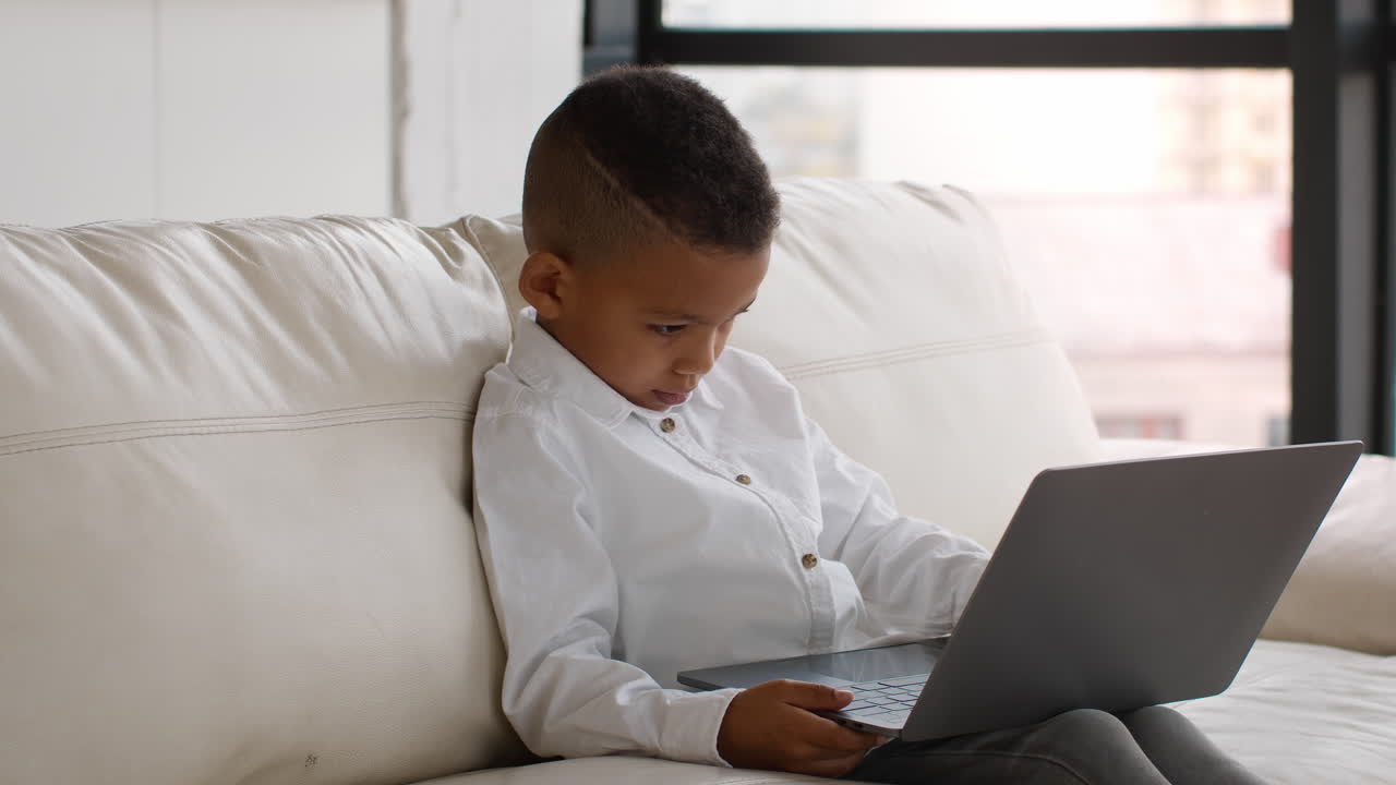 Young boy using laptop on a couch