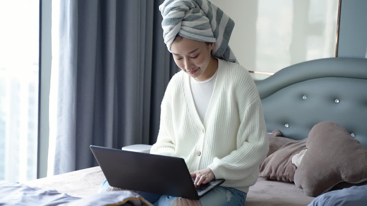 Woman working on laptop on bed