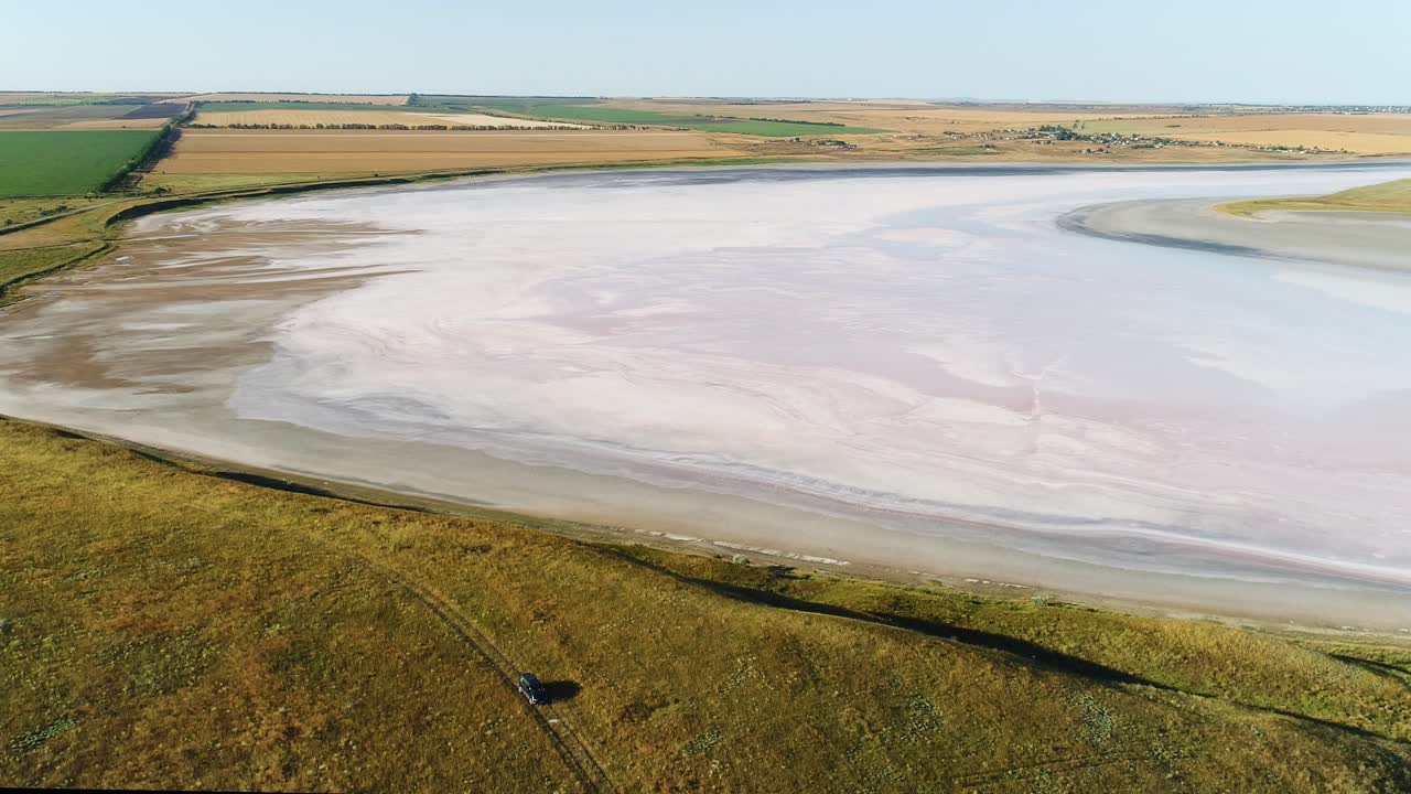 Luftfoto af en lyserød saltsø i et tørt landskab