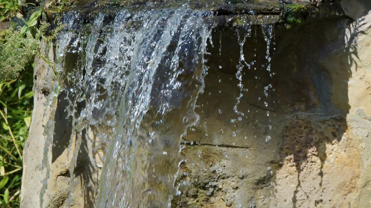 Clear water cascades over rugged stones in a sunlit Berlin park, sparkling in daylight