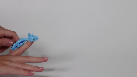 hand flings a blue dinosaur toy