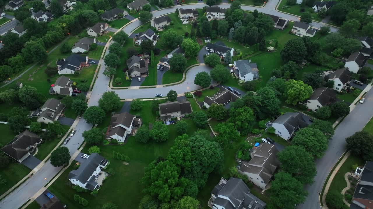 Quiet suburban neighborhood with winding streets, neatly arranged homes in USA.Peaceful ambiance is highlighted by spacious yards and tree-lined avenues, creating serene suburban setting. Aerial view.