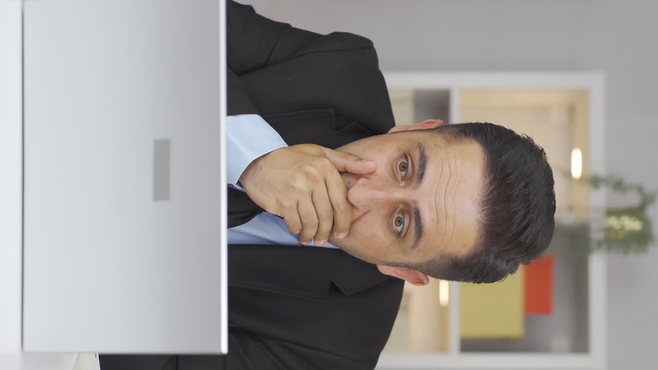 video vertical de un trabajador de oficina en casa leyendo malas noticias y sintiéndose frustrado.