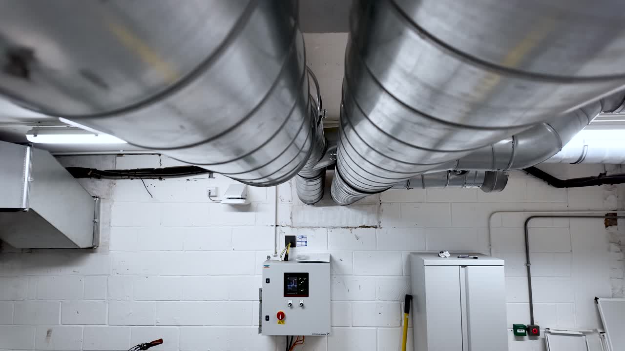 Industrial basement with metal ducts and a control panel, conveying a utilitarian, technical atmosphere