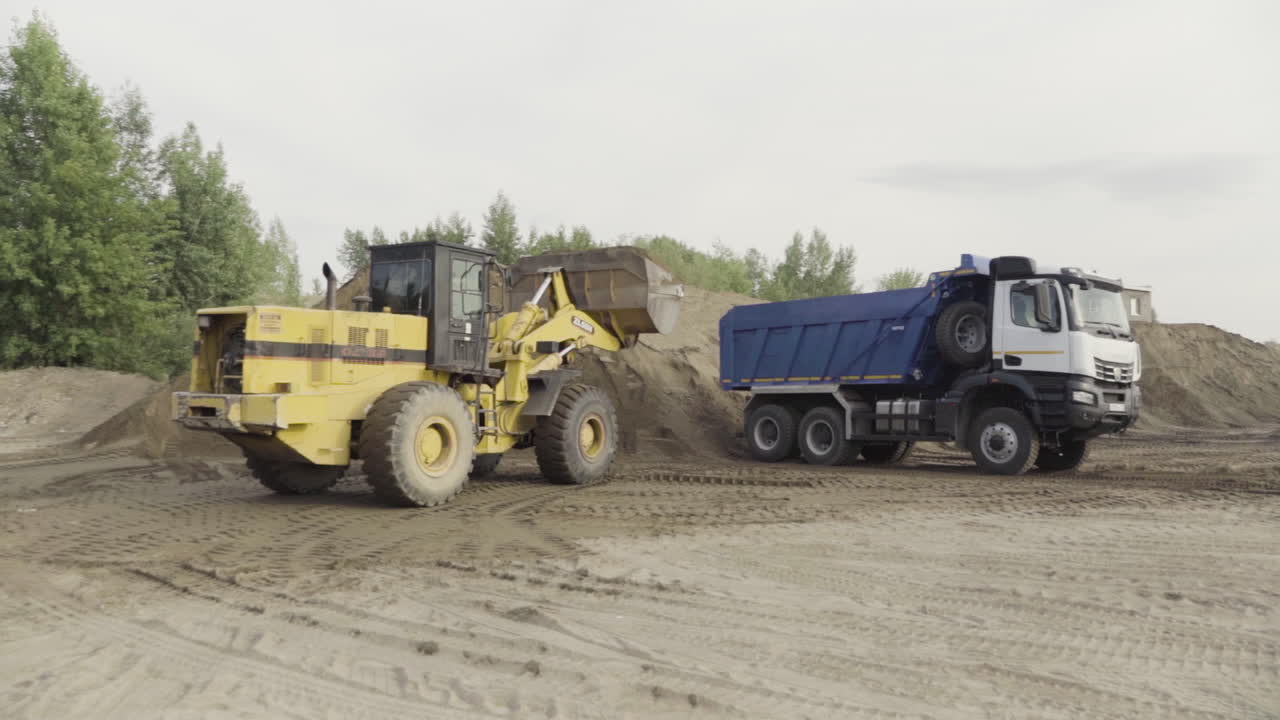 Excavator loading dump truck with construction materials