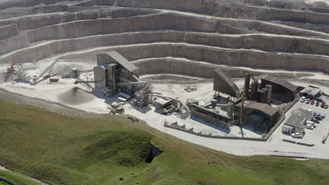 An-aerial-view-of-a-working-asphalt-quarry-building-with-the-quarry-cut-in-the-background,-Yorkshire,-UK