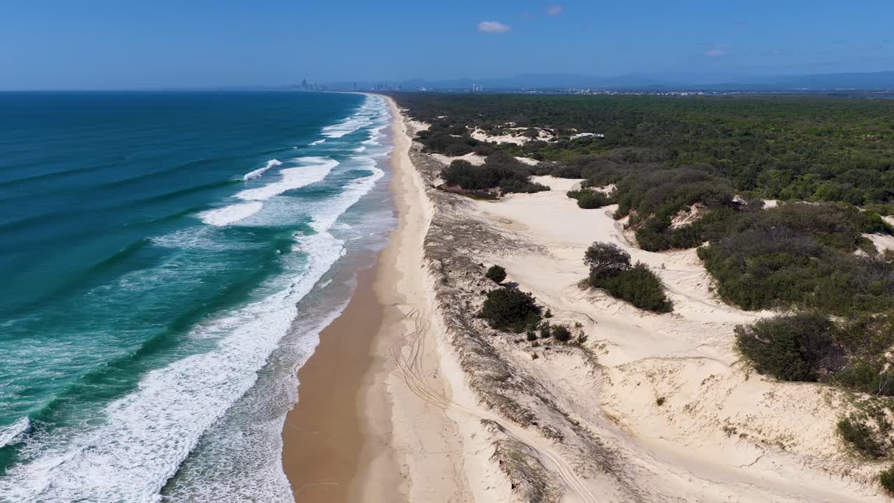 Uma foto aérea em ângulo alto feita por drone captura ondas do oceano turquesa quebrando contra uma praia de areia intocada em uma ilha