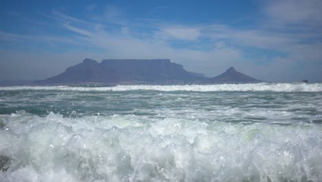 cámara lenta del océano atlántico con olas y la montaña de la mesa en el fondo