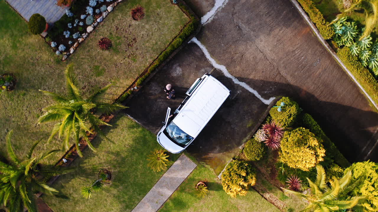 Vista aerea di amici che salgono in un'auto parcheggiata - dall'alto, ripresa con drone