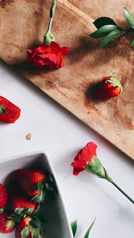 fresh strawberries and carnations on wooden board