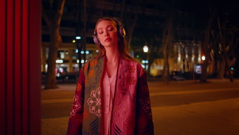 girl headphones posing night city street close up. woman listening music in town