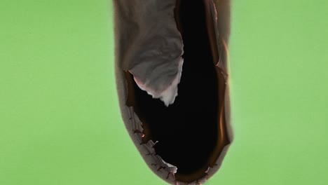 burning green paper on a black background. the hole in the center starts burning. the sheet of paper burns out completely.