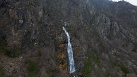 Vista-Aérea-De-Una-Majestuosa-Cascada-Que-Cae-Por-Un-Acantilado-Rocoso-Y-Empinado-En-Medio-De-Un-Paisaje-Montañoso-Escarpado