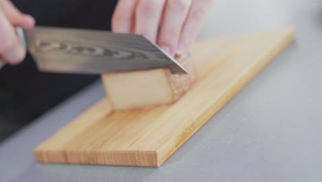 cuchillo afilado cortando una rebanada de un bloque de tofu ahumado