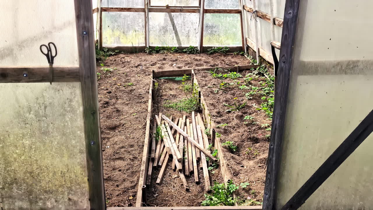 Empty greenhouse interior with wooden stakes and soil. Homegrown self-sustainable environment